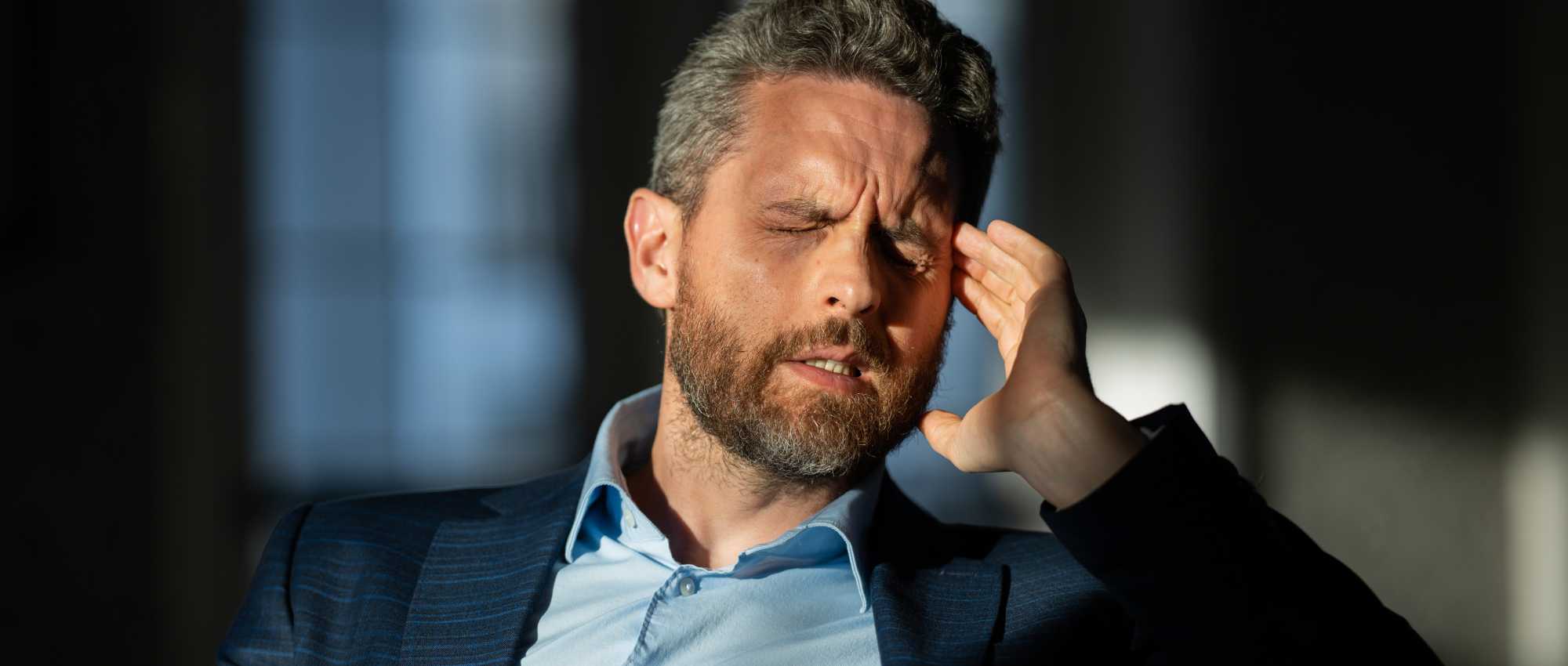 Ein Mann im Anzug hält sich das Ohr und zeigt Schmerzen, vermutlich durch Ohrendruck oder Barotrauma.​​​​​​​​​​​​​​​​​​​​​​​​​​​​​​​​​​​​​​​​​​​​