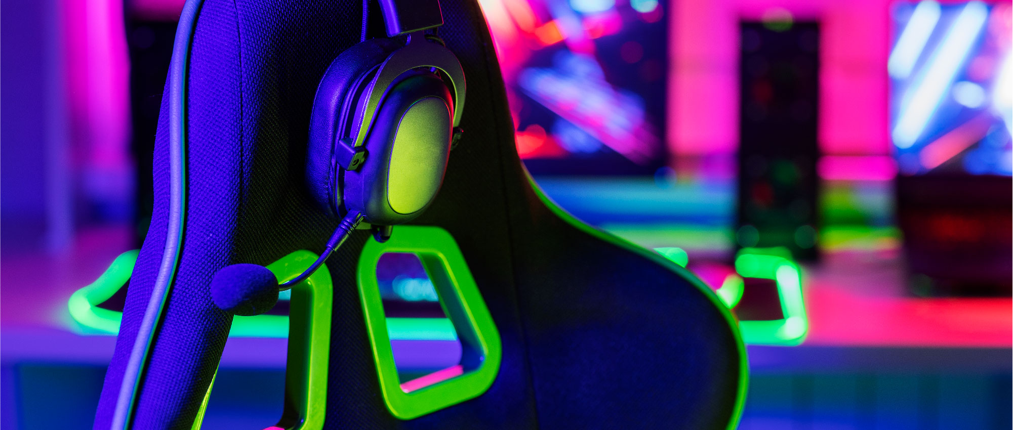 Nahaufnahme eines Gaming-Stuhls mit Headset vor farbig beleuchtetem Hintergrund in Gaming-Setup​​​​​​​​​​​​​​​​​​​​​​​​​​​​​​​​​​​​​​​​​​​​​​​​​​