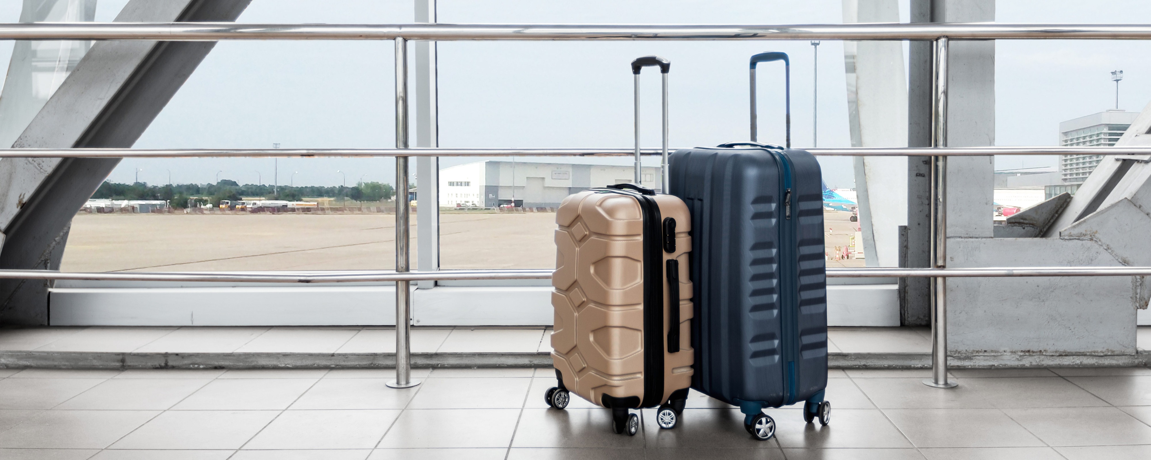 Zwei Hartschalenkoffer stehen am Flughafen vor Fenster mit Blick auf Rollfeld und Flugzeuge​​​​​​​​​​​​​​​​​​​​​​​​​​​​​​​​​​​​​​​​​​​​​​​​​​​​​​