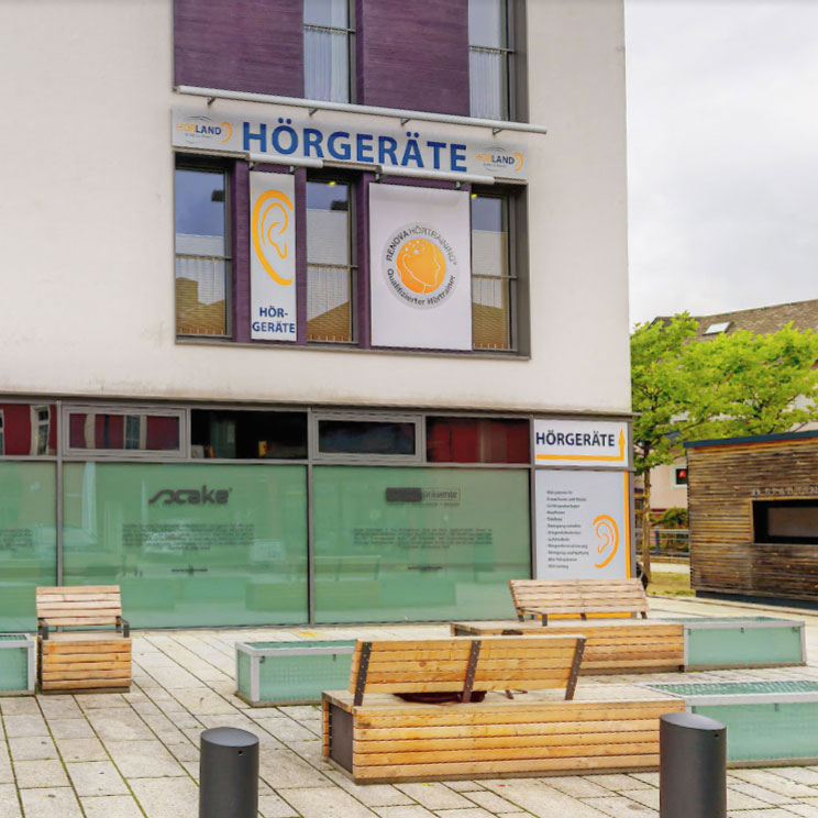 Hörgerätegeschäft in Münchberg mit Schaufenster, Sitzbänken und moderner Außenanlage bei bewölktem Himmel​​​​​​​​​​​​​​​​​​​​​​​​​​​​​​​​​​​​​​​​