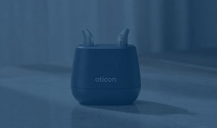 Zwei Oticon Hörgeräte im Ladegerät auf glatter Oberfläche mit unscharfem Hintergrund. Zubehör für Hörgeräte.​​​​​​​​​​​​​​​​​​​​​​​​​​​​​​​​​​​​​