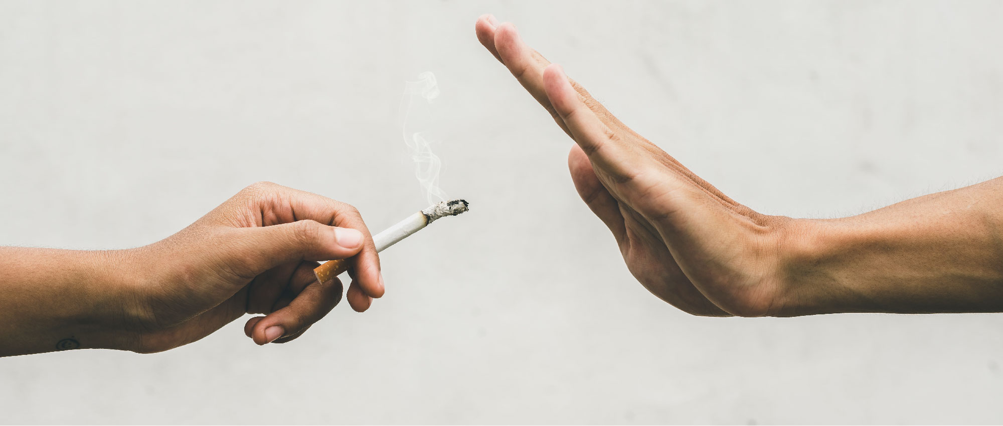 Zwei Hände vor hellem Hintergrund, eine hält Zigarette, die andere lehnt ab, Symbol für Rauchen aufhören.​​​​​​​​​​​​​​​​​​​​​​​​​​​​​​​​​​​​​​​​