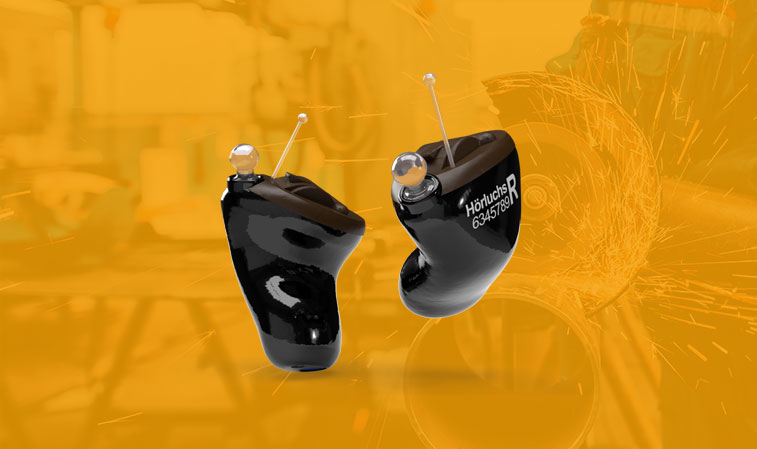 Zwei schwarze Hörgeräte mit Antennen vor orangefarbenem Hintergrund, Fokus auf modernes Hörgerätedesign​​​​​​​​​​​​​​​​​​​​​​​​​​​​​​​​​​​​​​​​​​