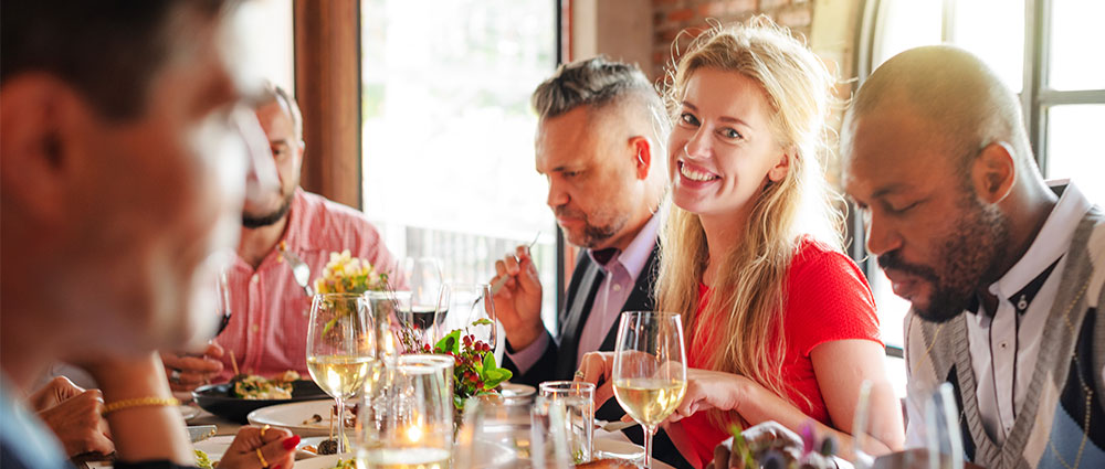 Mehrere Freunde sitzen an einem gedeckten Tisch und genießen gemeinsam Essen und Wein in entspannter Atmosphäre​​​​​​​​​​​​​​​​​​​​​​​​​​​​​​​​​​