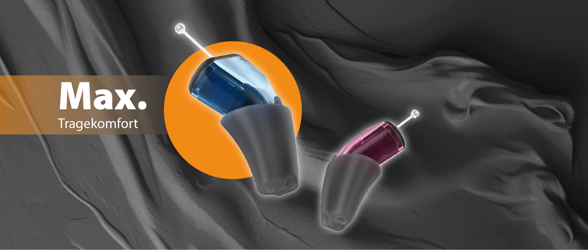 Zwei farbige In-Ear Hörgeräte auf schwarzem Stoff mit Fokus auf maximalen Tragekomfort und Details der Technik.​​​​​​​​​​​​​​​​​​​​​​​​​​​​​​​​​​