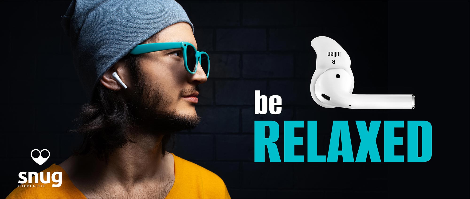 Junger Mann mit grauer Mütze und blauen Brillen trägt weiße kabellose Ohrhörer vor dunklem Hintergrund​​​​​​​​​​​​​​​​​​​​​​​​​​​​​​​​​​​​​​​​​​​