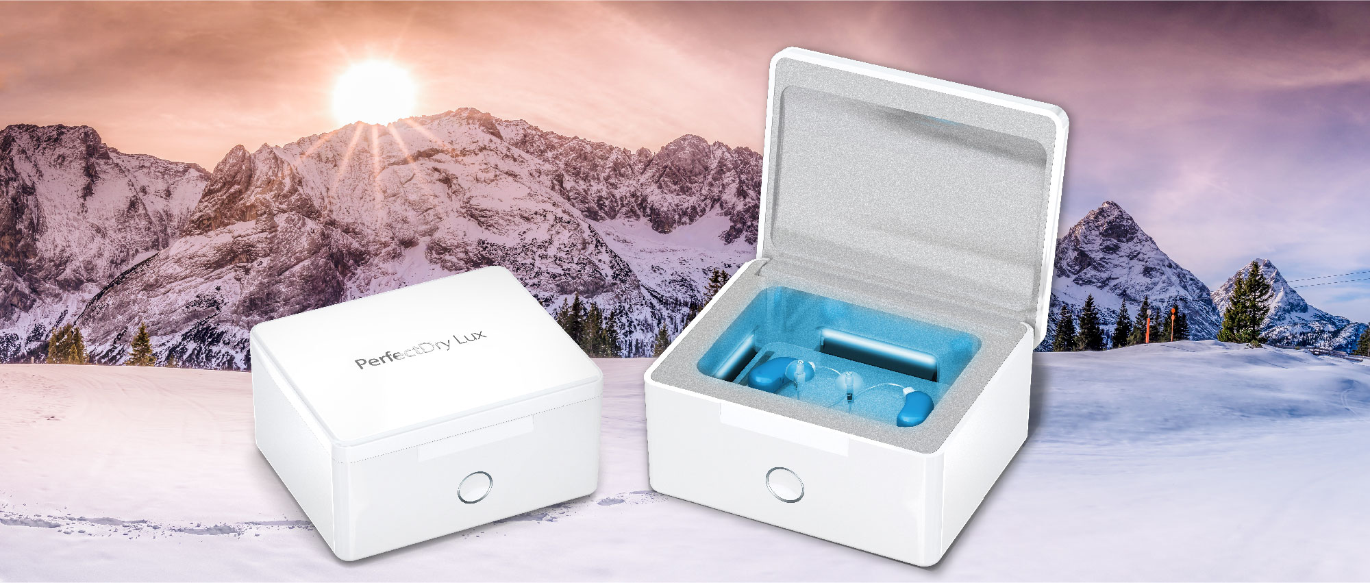 Weiße Trockenbox PerfectDry Lux mit geöffnetem Deckel und Hörgeräten vor verschneiten Bergen im Sonnenuntergang​​​​​​​​​​​​​​​​​​​​​​​​​​​​​​​​​​